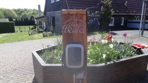 A wooden sign with 'Herzlich Willkommen Familie' text, a garden bed with flowers, and a brick pathway. - Holiday Bag WE1468 - Holiday Home (Sassnitz)