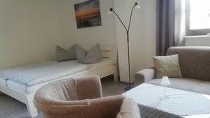 A small, cozy room with a single bed, a sofa, two armchairs, a table, and a floor lamp. - Holiday Bag WE1468 - Holiday Home (Sassnitz)
