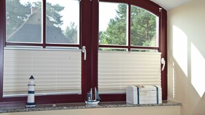 A room with a bay window, a small ship model, and a box on the windowsill.