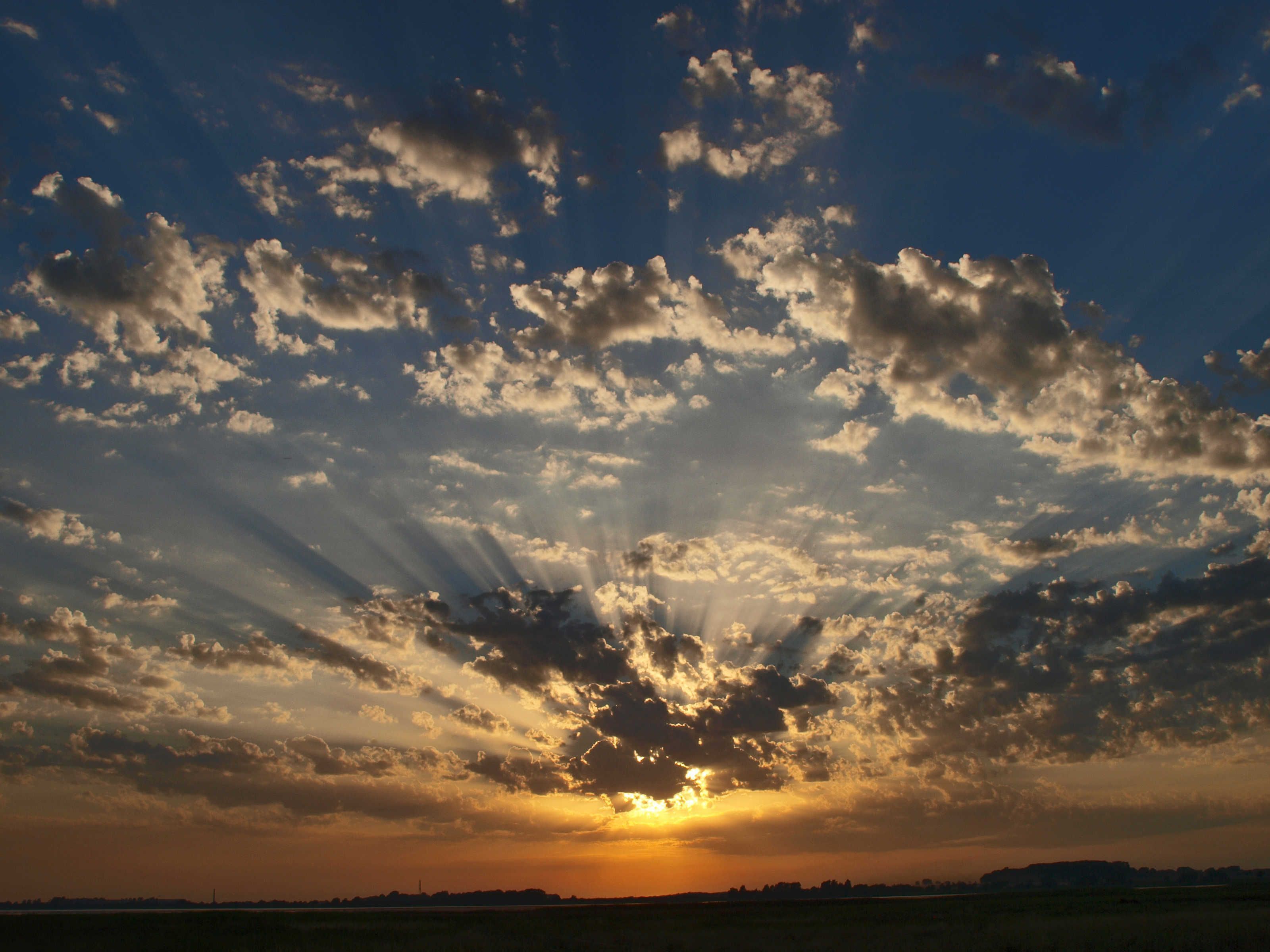 A sunset with clouds and a silhouette of a distant landscape.