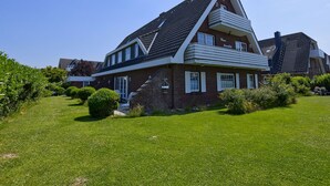 A modern two-story house with a sloped roof, a balcony on the upper floor, and a well-maintained lawn. - 005 - Hooge (BC.n3) - BUE - Apartment house Seewind (Büsum)