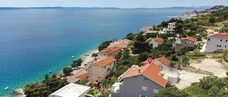 Un quartier résidentiel situé sur la côte, avec des maisons, une plage et une vue dégagée sur la mer.