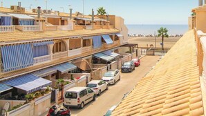 Eine Küstenstraße mit Gebäuden, geparkten Autos und einem Strand im Hintergrund.