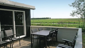 A patio with a table and chairs, a sliding glass door, and a view of a green field. - Lovely home in Sæby with WiFi (Sæby)