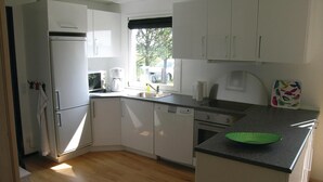 A modern kitchen with white cabinets, a dishwasher, a stove, and a window providing natural light. - Lovely home in Sæby with WiFi (Sæby)