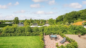 Un quartier résidentiel doté d’une pelouse bien entretenue, d’une terrasse avec mobilier d’extérieur et d’une vue sur les maisons et les arbres des environs.