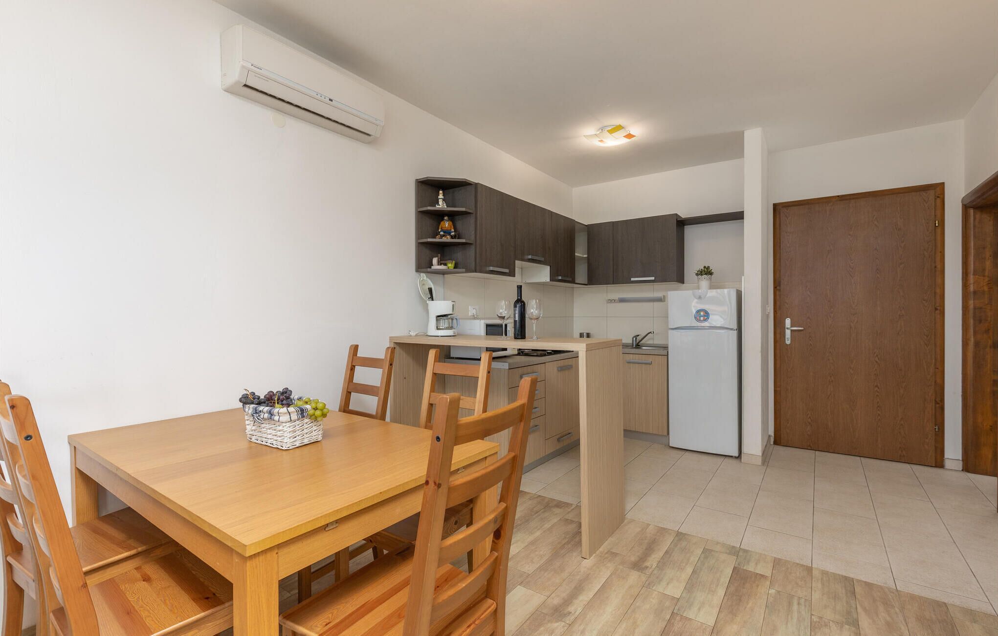 Una cocina compacta con comedor, muebles de madera y aire acondicionado integrado.