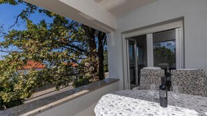 En balkon med et bord dækket til to, en vinflaske og et glas.