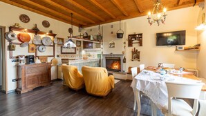 Ein gemütliches Wohnzimmer mit Kamin, Holzbalken und einem Essbereich mit Tisch für zwei Personen.