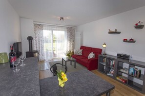 A living room with a red sofa, a coffee table, a bookshelf, and a fireplace. - Apartment 1 - Rügen-Fewo 280/1 (Dreschvitz)