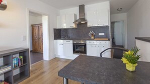 Een moderne keuken met witte kasten, een inbouwoven en een roestvrijstalen afzuigkap.