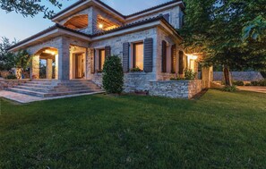 A stone house with a covered porch, steps leading to the entrance, and a well-maintained lawn. - Lovely home in Gorica (Gorica)