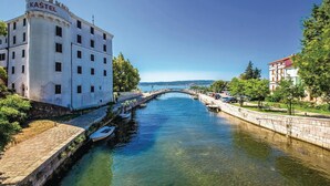 Un edificio con un cartel que dice "KAŠTEL" junto a un canal con barcos.