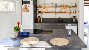 Une cuisine moderne dotée d’un îlot central, d’appareils électroménagers intégrés et d’étagères en bois.