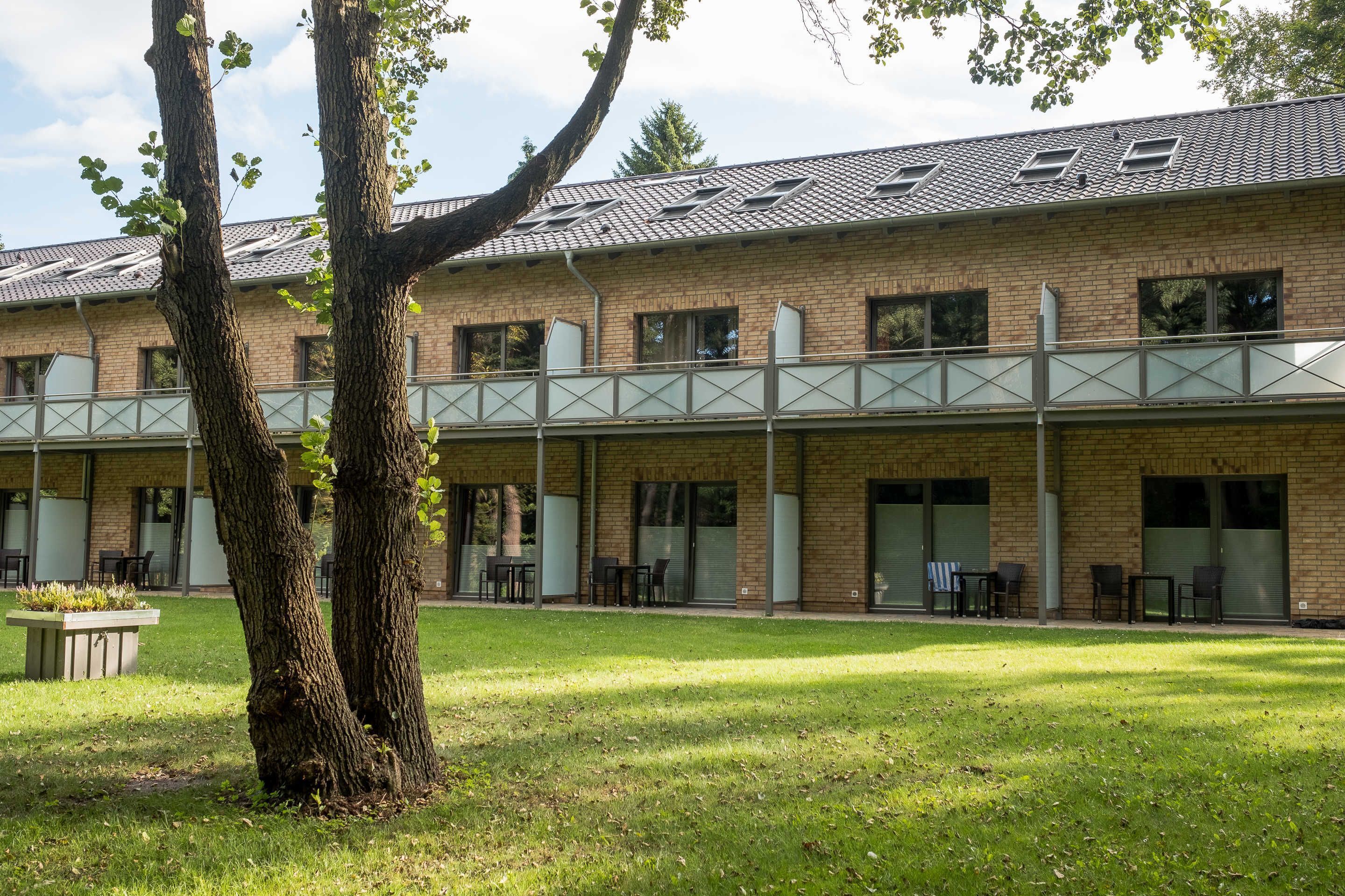A building with a brick facade, large windows, and a covered outdoor seating area with tables and chairs.