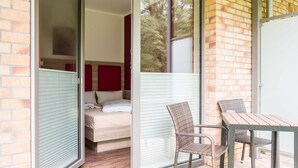 Una habitación con cama, una puerta corrediza de vidrio y una mesa con sillas.