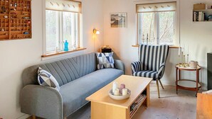 A cozy living room with a grey sofa, a striped armchair, a wooden coffee table, and a bookshelf filled with various items. - 1 bedroom lovely home in Kalundborg (Kalundborg)