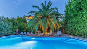 En swimmingpool med liggestole og en palme.