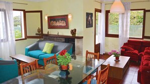 A dining area with a glass table and chairs, a blue sofa with a green pillow, and a red sofa. - Beach front home in Porto Cristo (Porto Cristo)