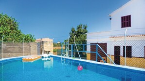 A swimming pool with a diving board, surrounded by a fence and a building with a red window. - Beach front home in Porto Cristo (Porto Cristo)