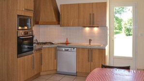 Eine kleine Küche mit Holdekor, einem Backofen, einer Mikrowelle, einem Geschirrspüler und einem Spülbecken.