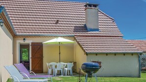 Ein Haus mit Ziegeldach, einer Terrasse mit Gartenmöbeln und einem Grill.