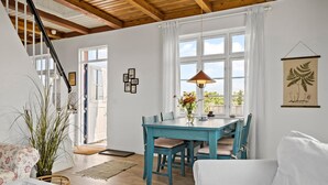 Ein geräumiges Wohnzimmer mit Essbereich, Holzbalken an der Decke und großen Fenstern.