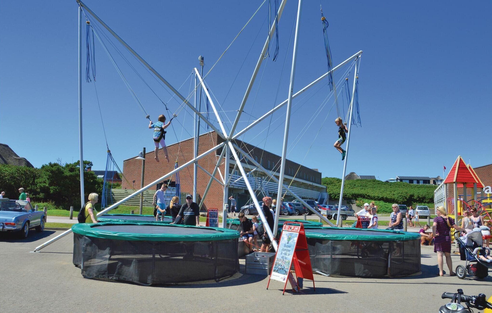 A trampoline park with multiple trampolines and a large building in the background.