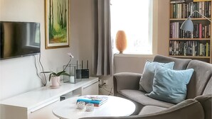 A modern living room with a flat-screen TV, a bookshelf, a coffee table, and a grey sofa with blue cushions. - Stunning home in Tingstäde with WiFi (Tingstäde)