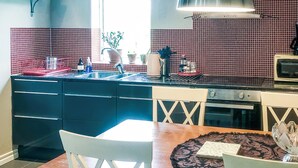 A kitchen with a red tiled backsplash, a stove, and a sink. There are two white chairs and a table with a placemat. - Stunning home in Tingstäde with WiFi (Tingstäde)