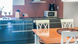 A modern kitchen with a black refrigerator, a microwave, and a coffee maker on the counter. There are two white chairs and a wooden table with a patterned placemat. - Stunning home in Tingstäde with WiFi (Tingstäde)