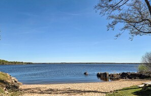 Vista de un lago con playa de arena, agua tranquila y cielo despejado.