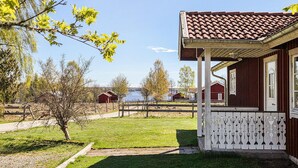 Un bâtiment rouge avec un porche blanc et un toit en tuiles, entouré d’une pelouse et d’arbres.