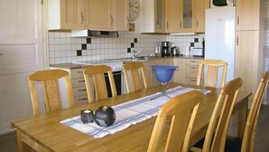 Une cuisine avec des meubles de rangement en bois, une cuisinière, un évier et une horloge au mur.