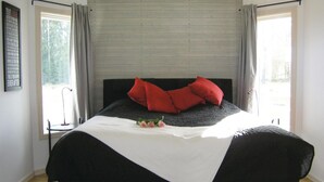 Une chambre à coucher avec un lit, une table de chevet et une fenêtre avec des rideaux.