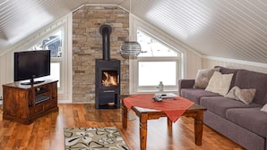 A cozy attic living room with a stone fireplace, wooden furniture, and a television. - Lovely home in Rauland with sauna (Rauland)
