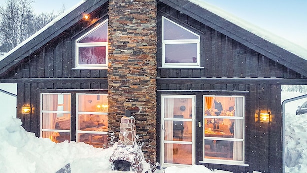 A two-story log cabin with a stone chimney, large windows, and a snow-covered landscape. - Lovely home in Rauland with sauna (Rauland)