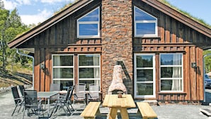 A rustic cabin with a stone chimney, large windows, and a picnic table in front. - Lovely home in Rauland with sauna (Rauland)