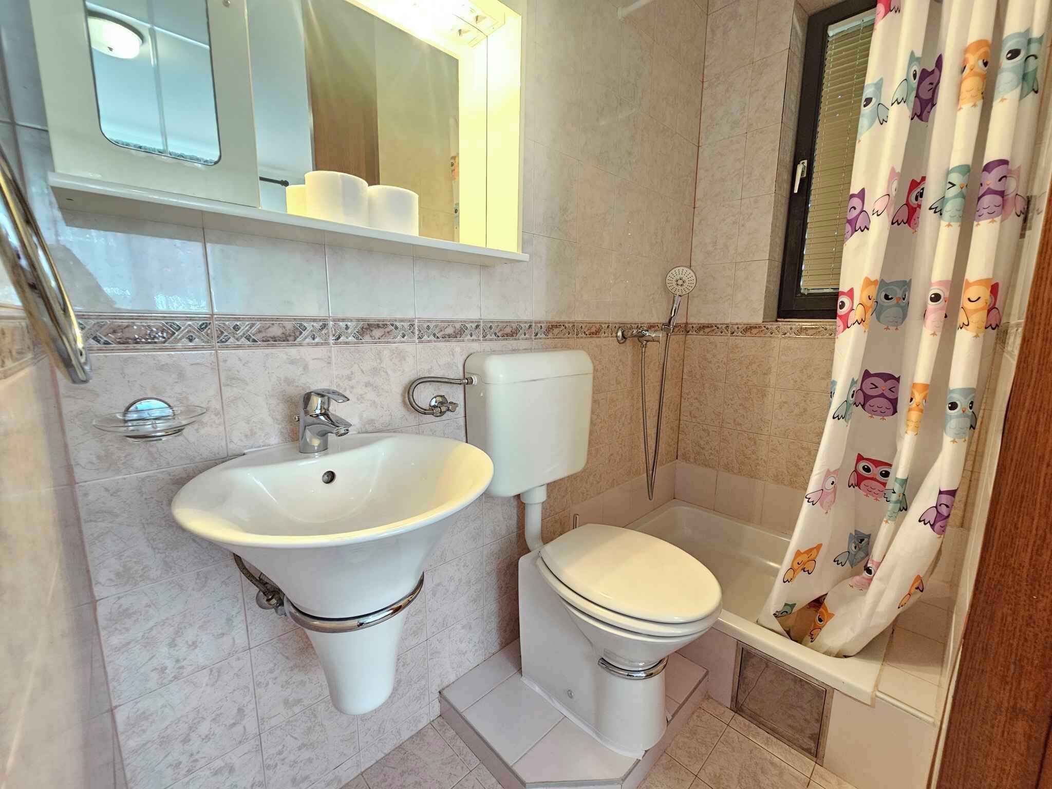 A bathroom with a sink, toilet, and shower curtain.