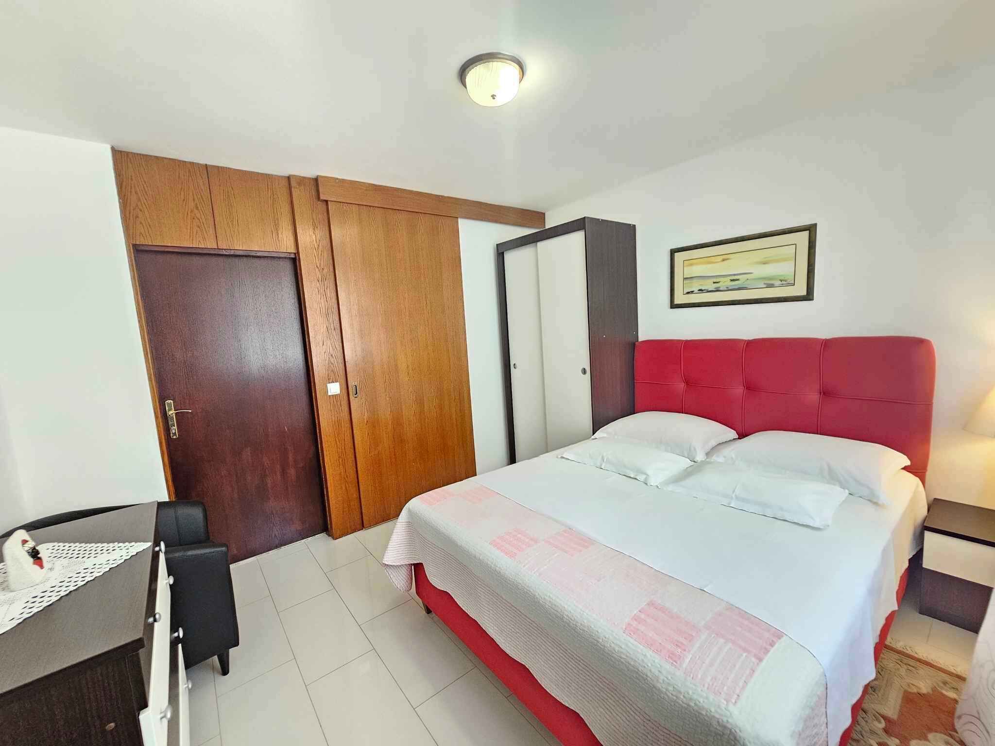 A bedroom with a bed, a desk, a chair, and a wardrobe.