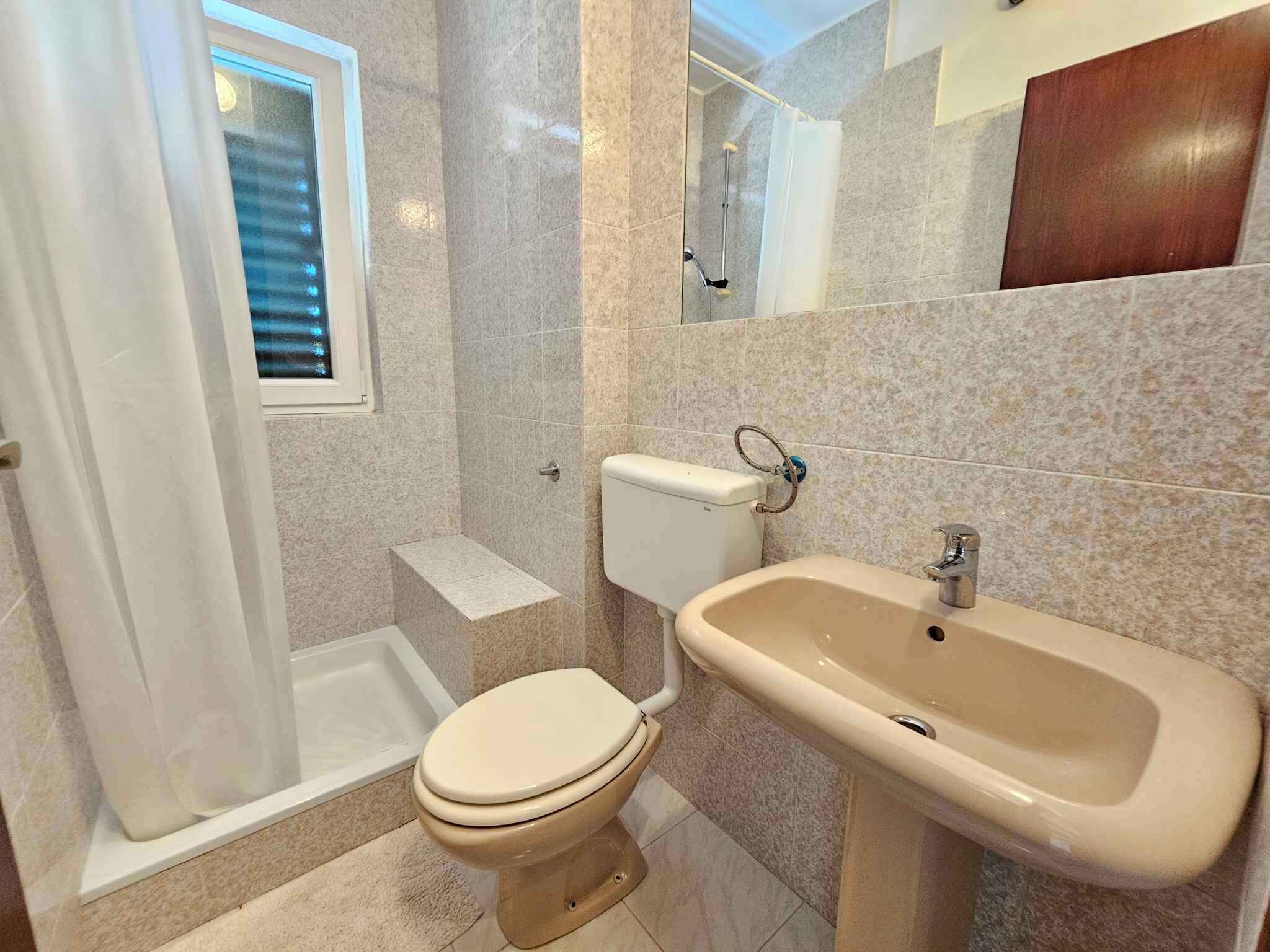 A bathroom with a toilet, sink, and shower area.