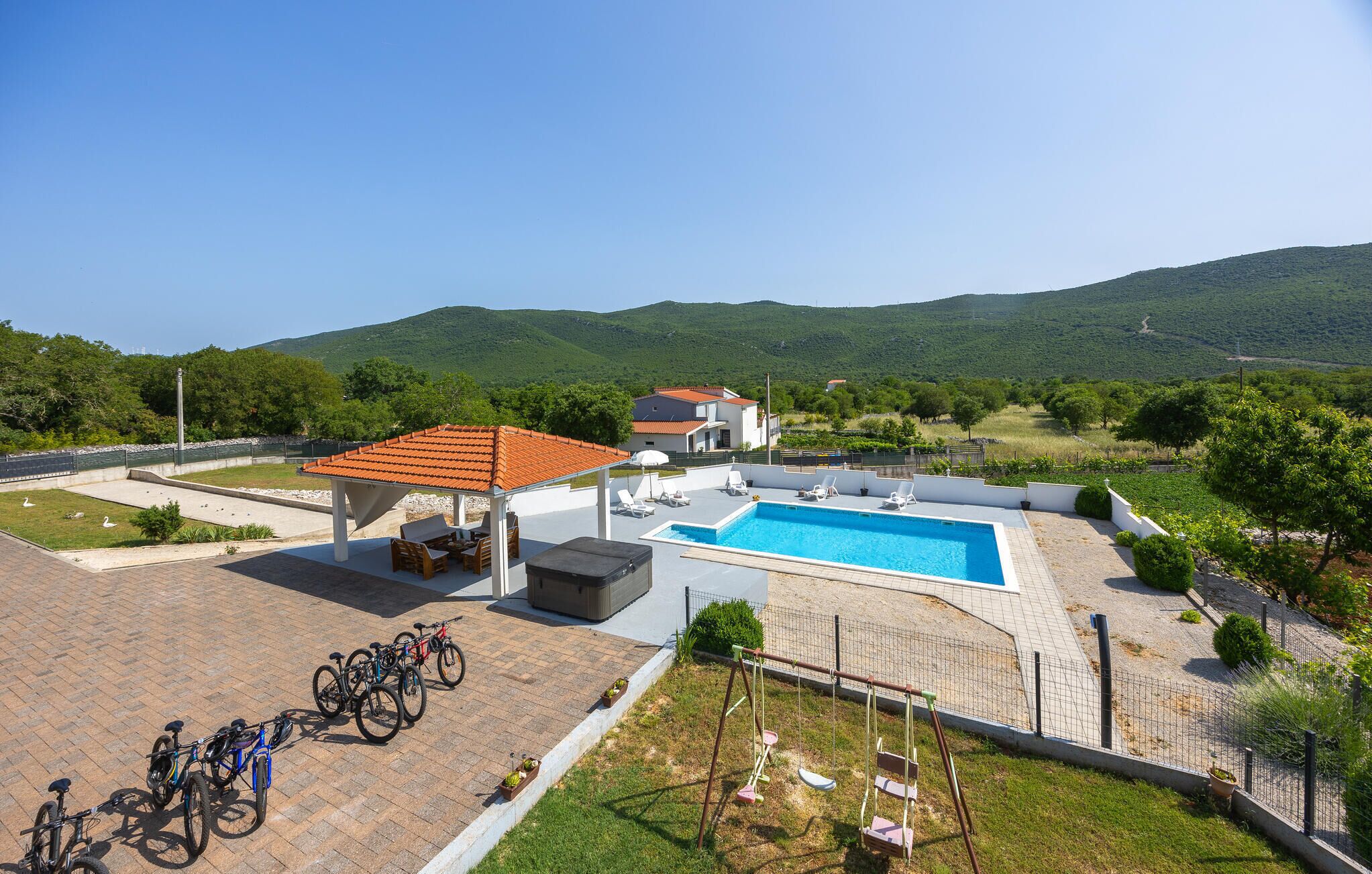 A rooftop pool area with a covered seating area, a swimming pool, and bicycles parked nearby.