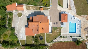 Propiedad residencial con piscina, varias construcciones con techo y un césped cuidado.