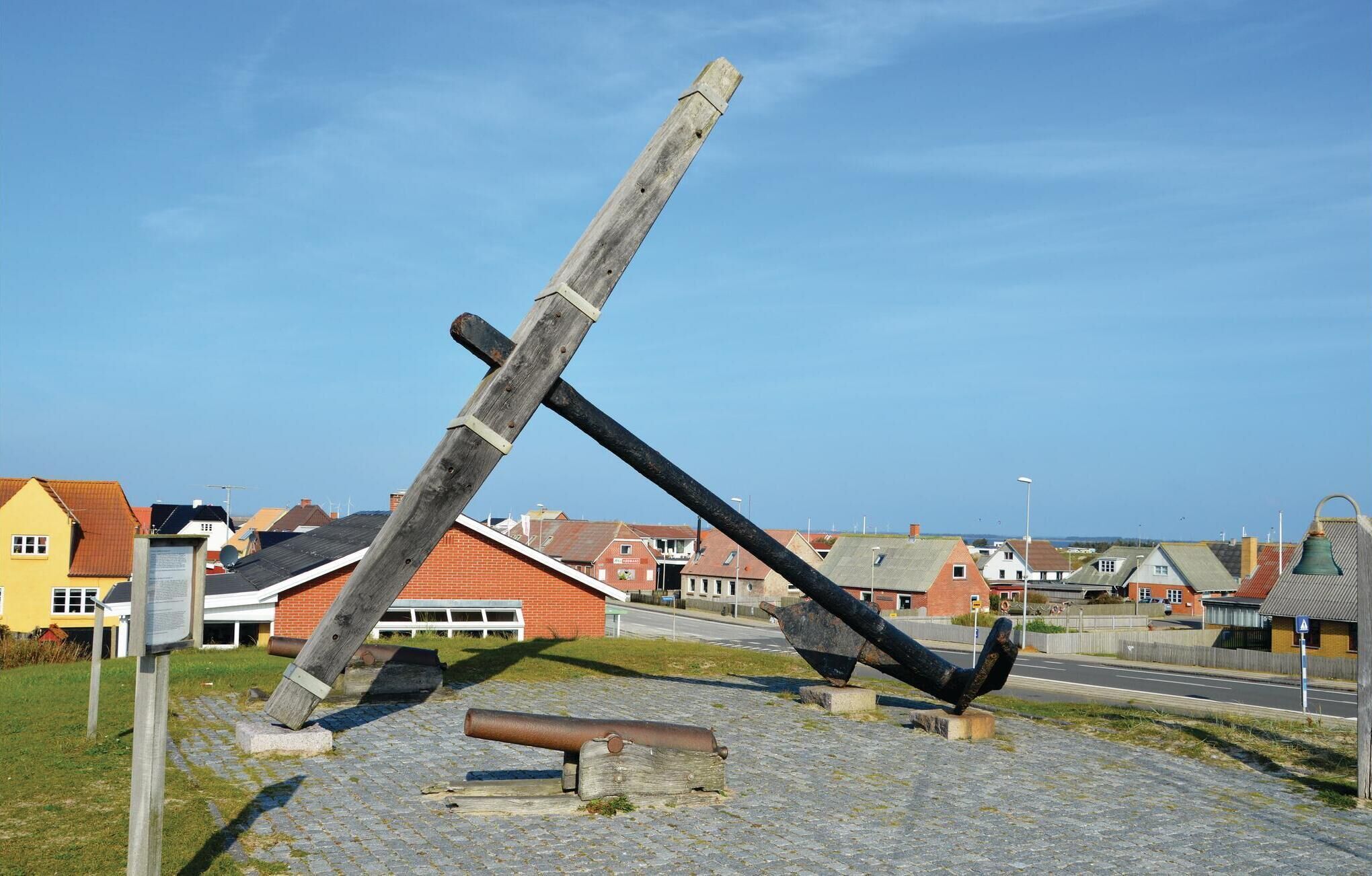 A large, tilted wooden structure resembling a ship's mast, with a cannon and a smaller wooden piece on the ground.