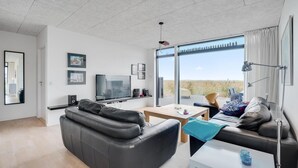 A modern living room with a leather sofa, a TV, and a dining table. - 2 bedroom lovely home in Ulfborg (Ulfborg)