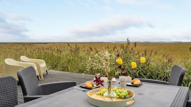 A dining table with wicker chairs, a vase with flowers, and a plate of grapes and bread. - 2 bedroom lovely home in Ulfborg (Ulfborg)