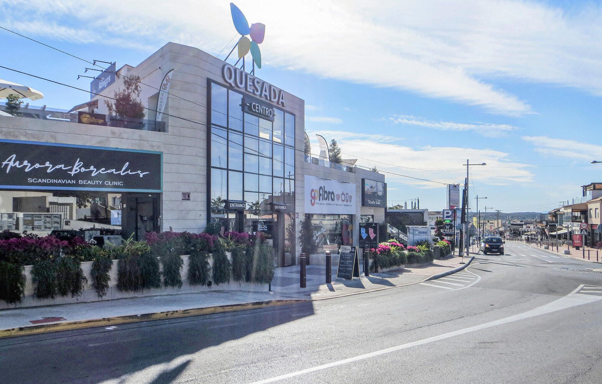 Straßenansicht mit einem Gebäude, auf dem 'Quesada Centro' und 'Arova Boricua Scandinavian Beauty Clinic' steht.