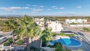 Een woonwijk met een zwembad, palmbomen en huizen in mediterrane stijl.