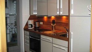 A modern kitchen with white cabinets, a wooden countertop, a coffee maker, a knife block, and a stainless steel sink. - Apartment Dompfaff - apartment bullfinch (Zinnowitz)