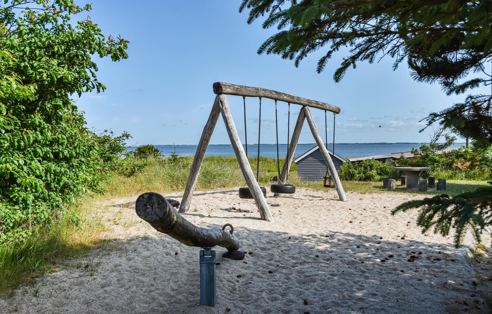 Legehus med gyngestol og dækkenet på en sandstrand med udsigt over havet.